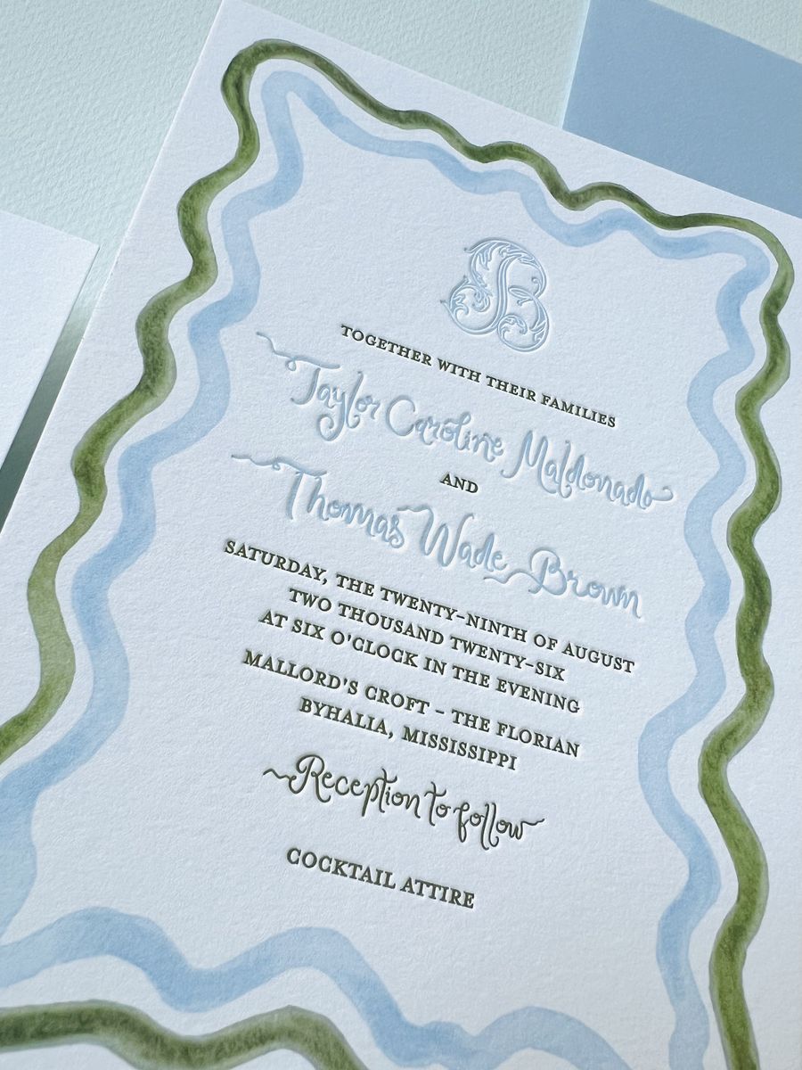Letterpress wedding invitation with a wavy blue and green scalloped border and a monogram